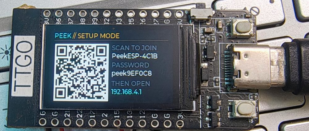 The device in setup mode, showing a QR code beside the access point name PeekESP-4C1B, its generated password, and the address 192.168.4.1.